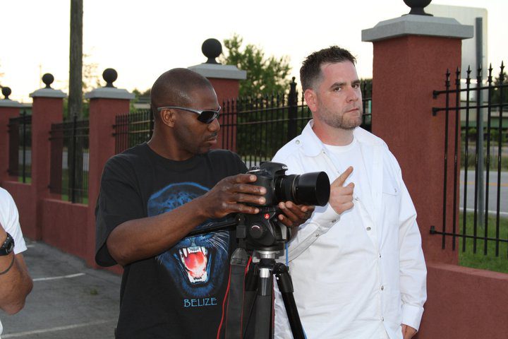 Photographer with camera and man in chef outfit outdoors.