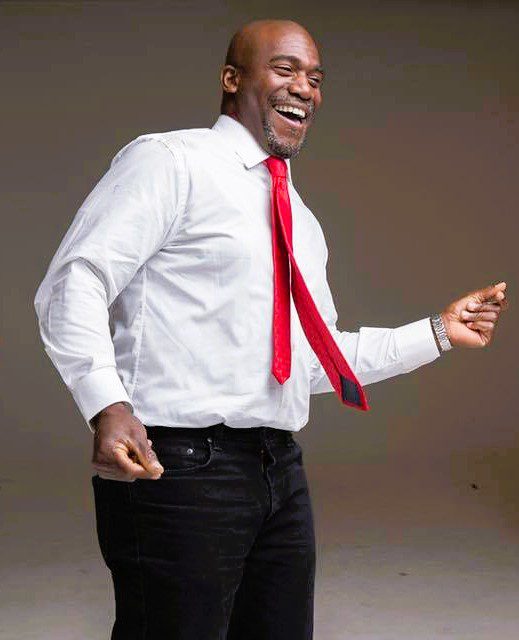 Smiling man in white shirt and red tie dancing joyfully.